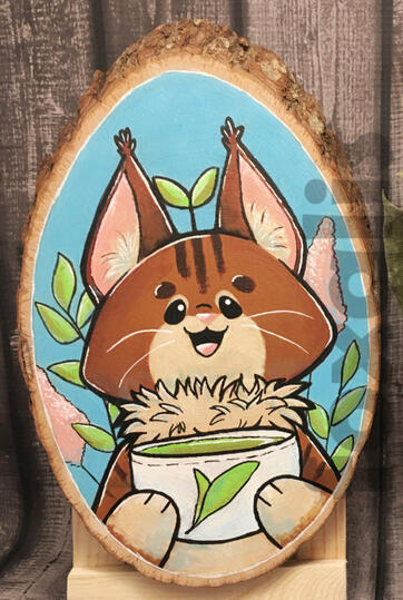 A photo of an acrylic painting on a wood slice. It is of a cartoon cat holding a cup of tea. Around it are some flowers and leaves.